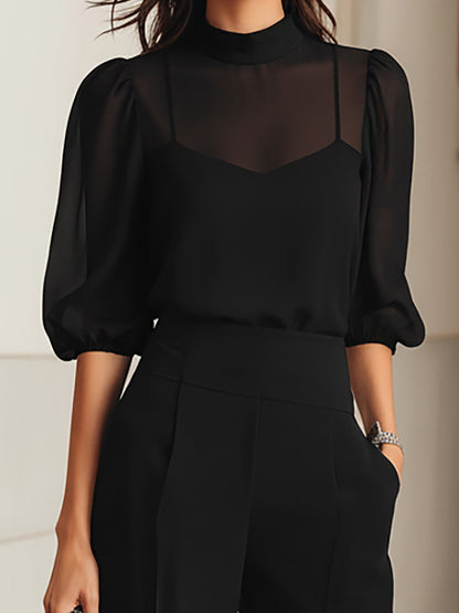 Close-up of the black sheer high-neck top with puff sleeves layered over a camisole, worn with high-waisted trousers. 7