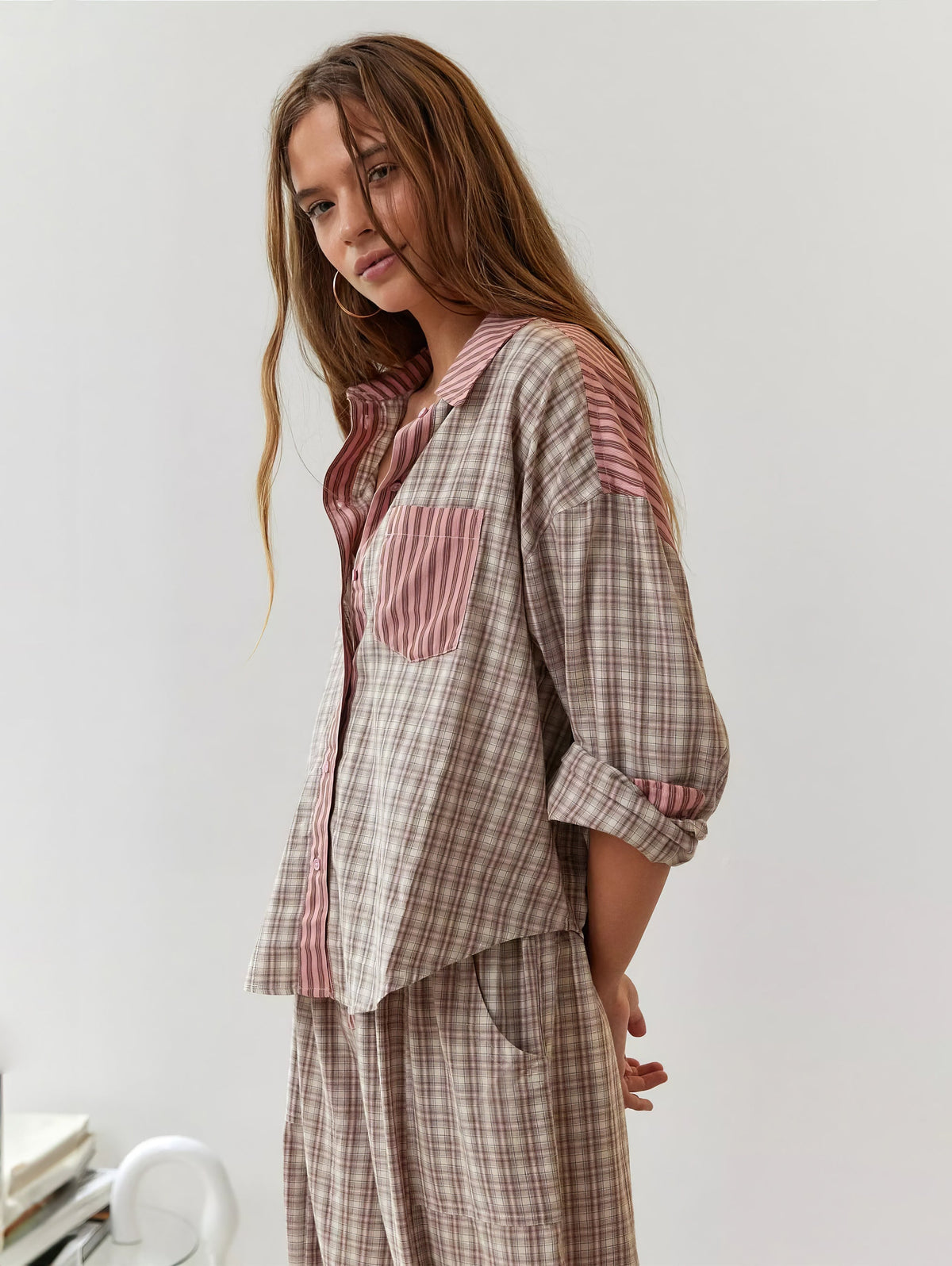 Model in the pink-and-beige check pyjama set with striped collar and pocket, shown from the side with sleeves pushed up. 2