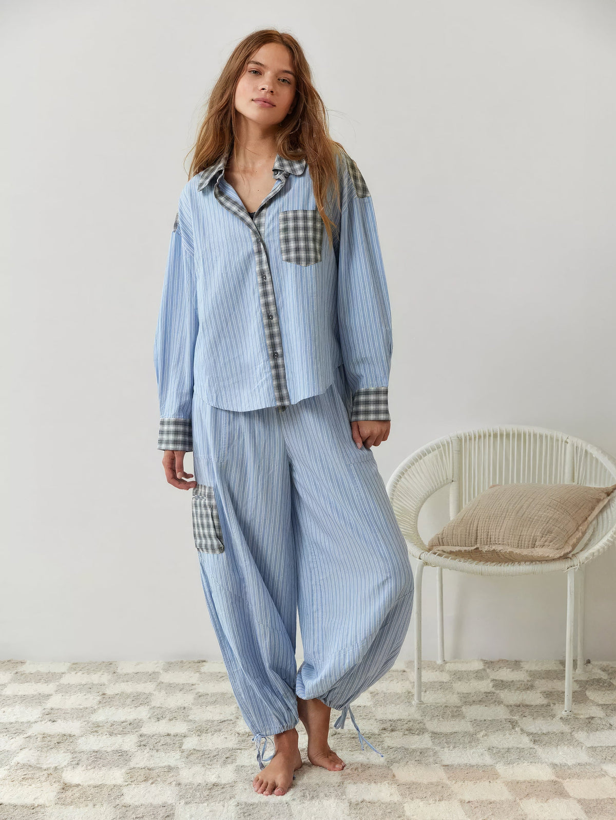 Full-length shot of the blue-striped pyjama set on a barefoot model, showing the baggy trousers with grey check pocket and ankle ties. 7