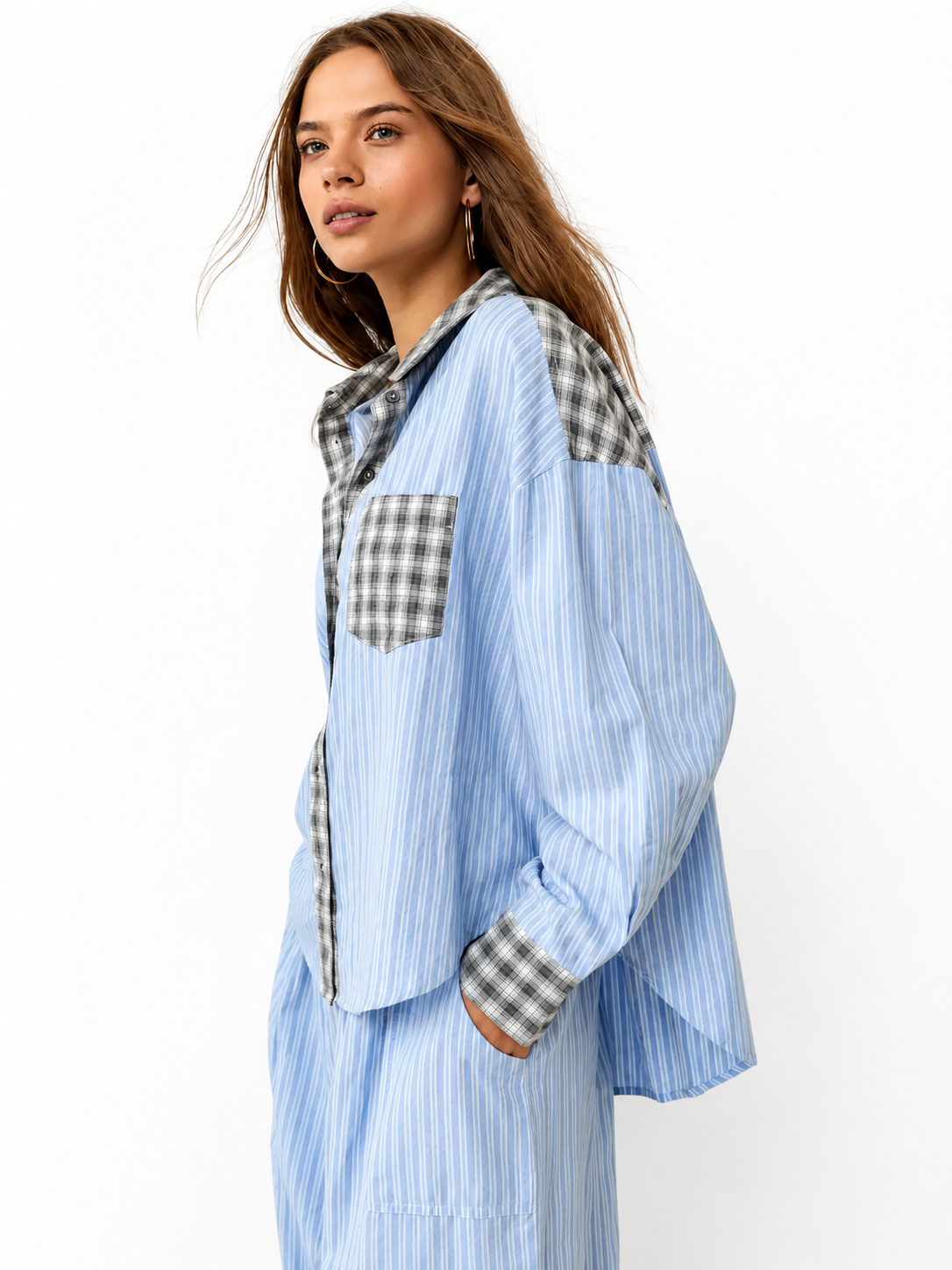 Model in the blue-striped pyjama shirt with grey check shoulders, collar and pocket, turned to the side with one hand in a pocket. 1
