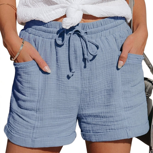 Model wearing crinkled light blue shorts with hands in the patch pockets, front view 1