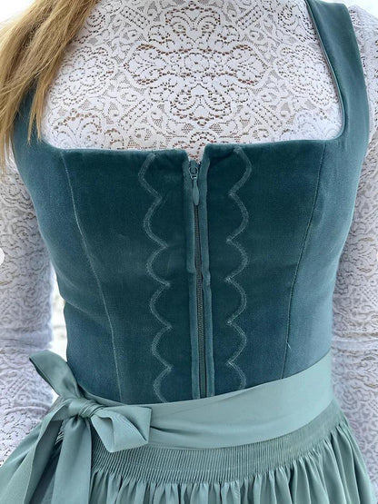 Close-up of the velvet bodice front showing the central zip, scalloped embroidered trim and the apron's bow at the waist. 2