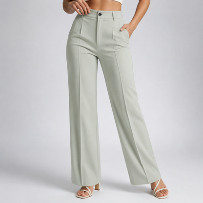 Model wearing pale sage-green high-waisted trousers with centre creases and one hand in the pocket, with cream strappy heels 23