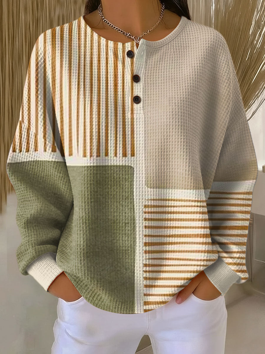 Waffle knit henley jumper in colour-block panels of sage green, cream and mustard stripes, worn with white trousers 1