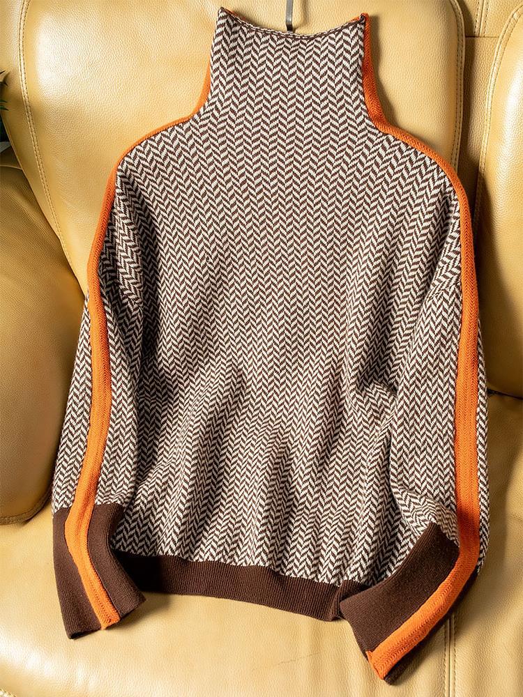 Brown and cream herringbone jumper laid flat on a tan leather sofa, showing the orange side stripes, brown hem and cuffs. 5