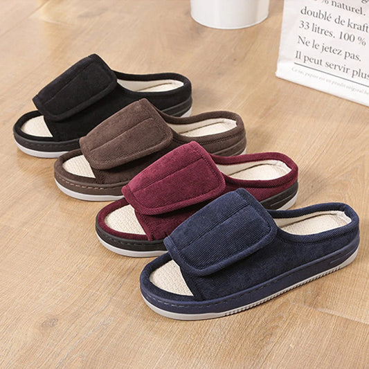 Four open-toe corduroy slippers in black, brown, burgundy and navy lined up on a wooden floor, each with a wide strap. 2