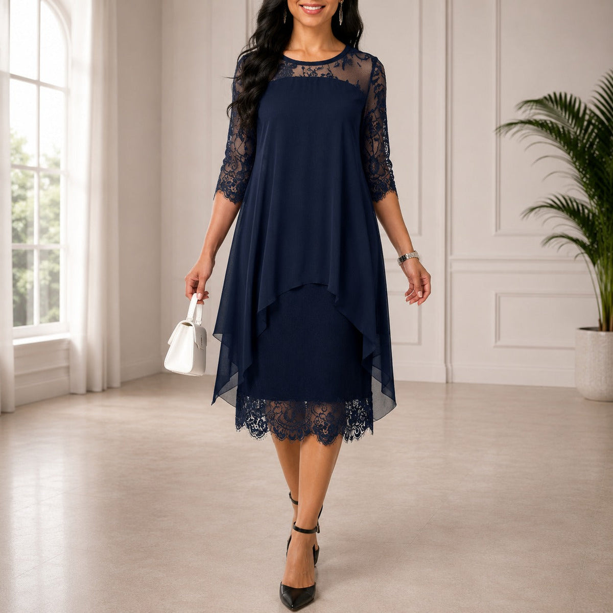 Model wearing the navy layered chiffon dress with lace sleeves and scalloped lace hem in a bright room 1