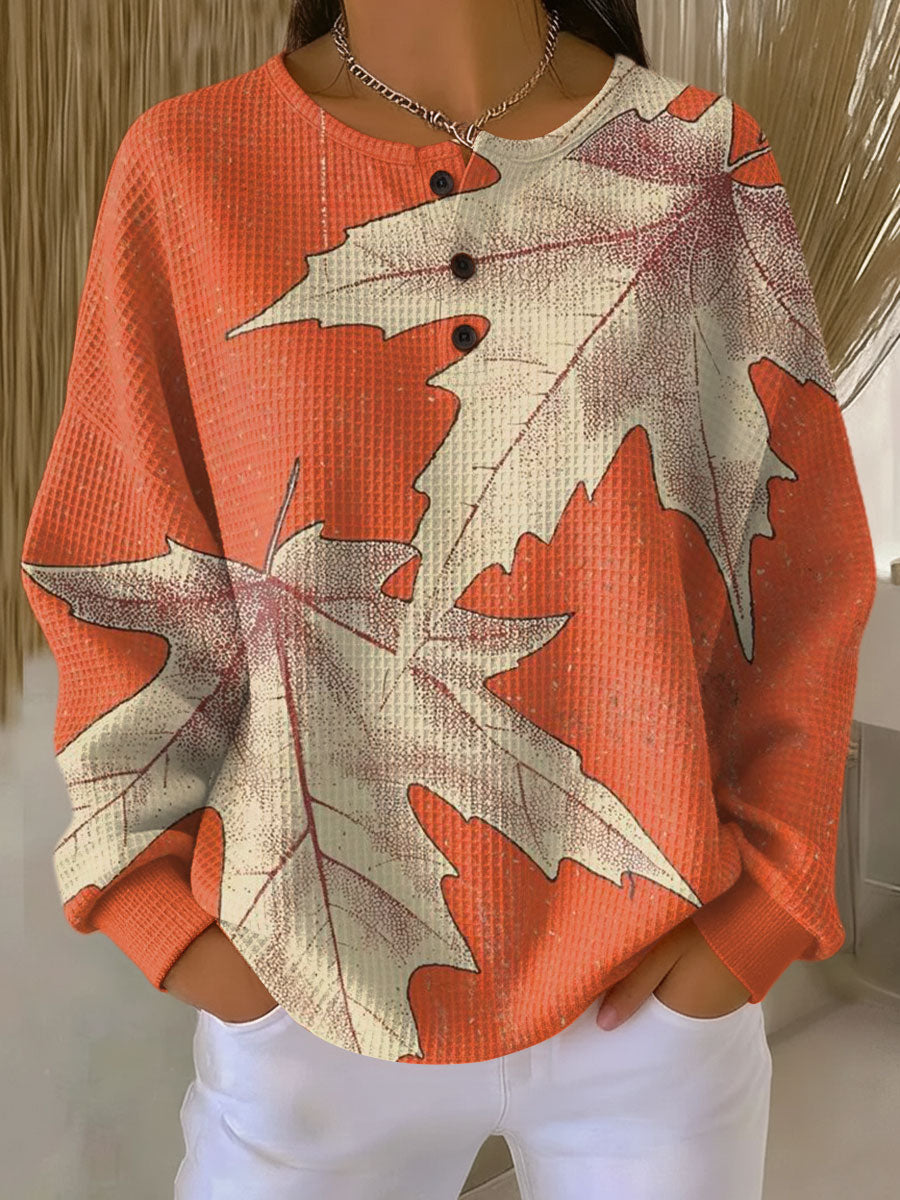 Orange waffle knit henley jumper printed with large cream maple leaves, worn with white trousers 14