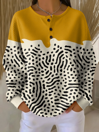 Waffle knit henley jumper with a mustard yellow yoke and cream lower half covered in black squiggles and dots 13
