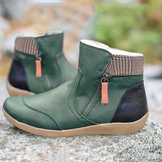 Pair of dark green leather ankle boots with side zip, houndstooth collar, black heel panel and tan sole, set on a rock. 1