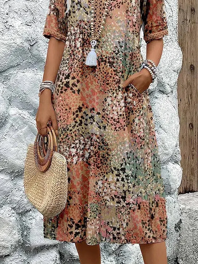 Close-up of the lower half in the earthy print, showing the side pocket, tiered skirt hem and a round straw handbag. 7