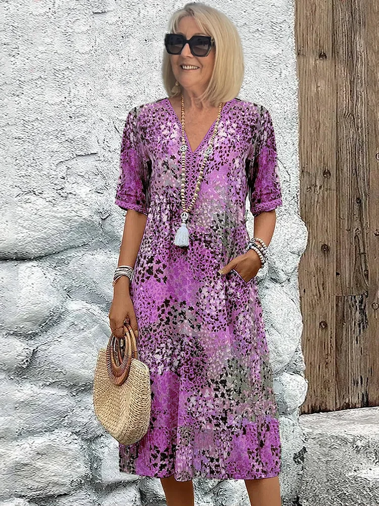 Loose V-neck midi dress in a purple and lilac speckled print, styled with sunglasses, bracelets and a straw bag. 4