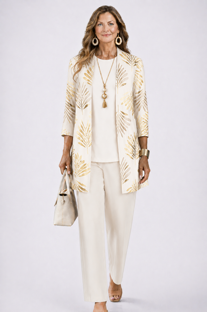 Model wears the cream set with a gold palm-leaf print on the open cardigan, carrying a handbag 3