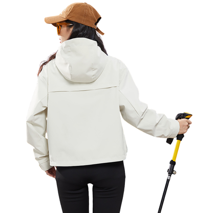Back view of the cream jacket on a model holding a trekking pole, showing the hood and the yoke seam across the shoulders. 5