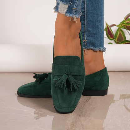 Close-up of dark green tasselled loafers worn with frayed jeans, showing the front tassel detail 24
