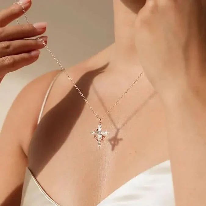 Model in a white camisole holds up a fine chain with a sparkling cross pendant 1