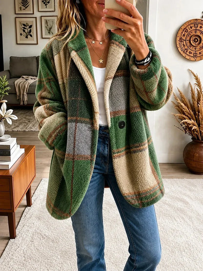 Model wearing the textured fluffy coat in a green, grey and beige check, with one button and hands in the pockets. 7
