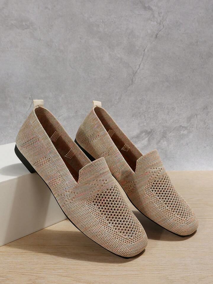 Pair of beige speckled knit slip-ons with perforated toes and a heel pull tab, leaning against a white block. 7