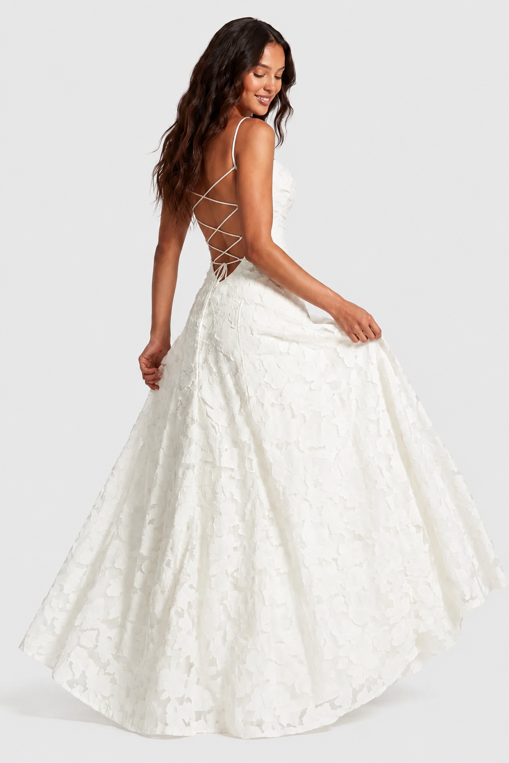 Ivory lace gown from behind, model swishing the skirt, with criss-cross lacing across the open back. 8