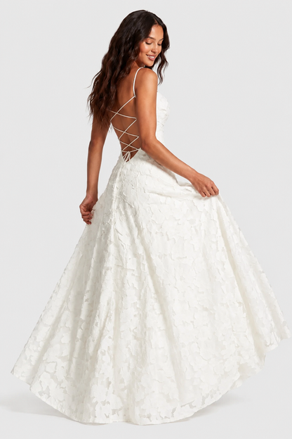 Ivory lace gown from behind, model swishing the skirt, with criss-cross lacing across the open back. 8