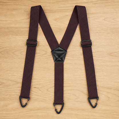 Dark burgundy Y-back suspenders laid flat on a wooden surface, with black adjusters, centre patch and three black clips. 17