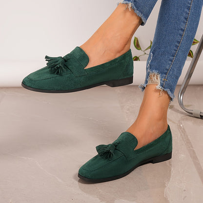 Green tasselled loafers on a model's feet, wearing frayed jeans, side view 10
