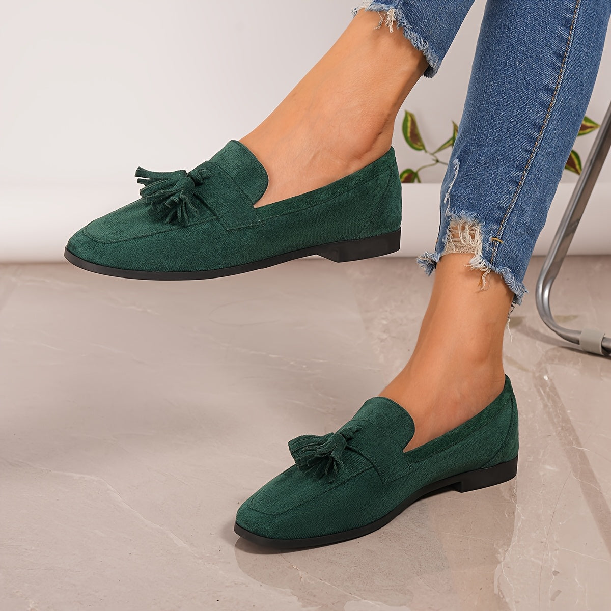Dark green tasselled loafers worn by a model with ripped jeans, one foot raised 22