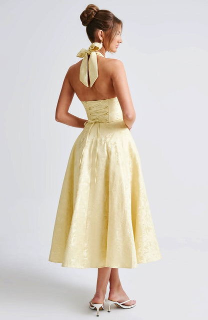 Back view of the pale yellow halter dress, showing the neck bow, open upper back and lace-up corset closure. 5