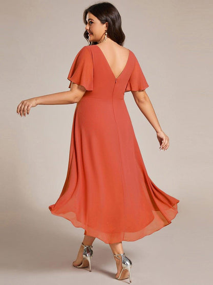 Back of the burnt orange dress on a plus-size model, showing the V back, zip and swirling high-low skirt. 98
