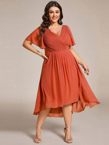 Plus-size model in the burnt orange chiffon dress, front view, hand on hip, with gold-toned strappy heels. 97