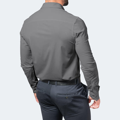 Back view of a model in a grey long-sleeved shirt with a plain yoke, tucked into navy trousers with a black belt. 6