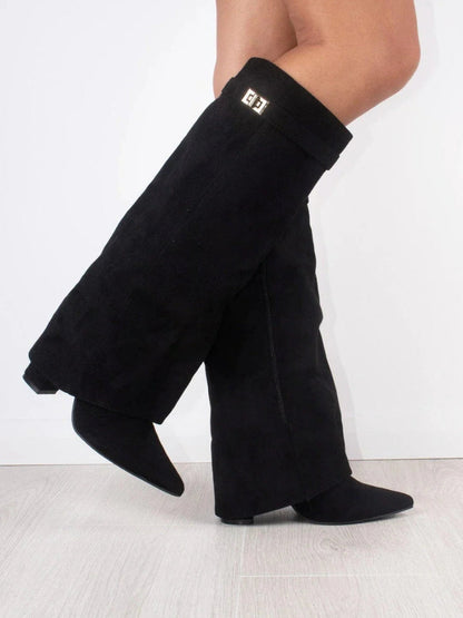 Black suede-look fold-over boots worn by a model mid-step, showing the gold turn-lock strap and a side zip. 2