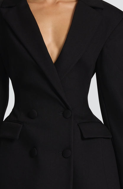 Close-up detail of the black blazer dress, showing the plunging lapels, covered buttons, flap pockets and fitted waist. 12