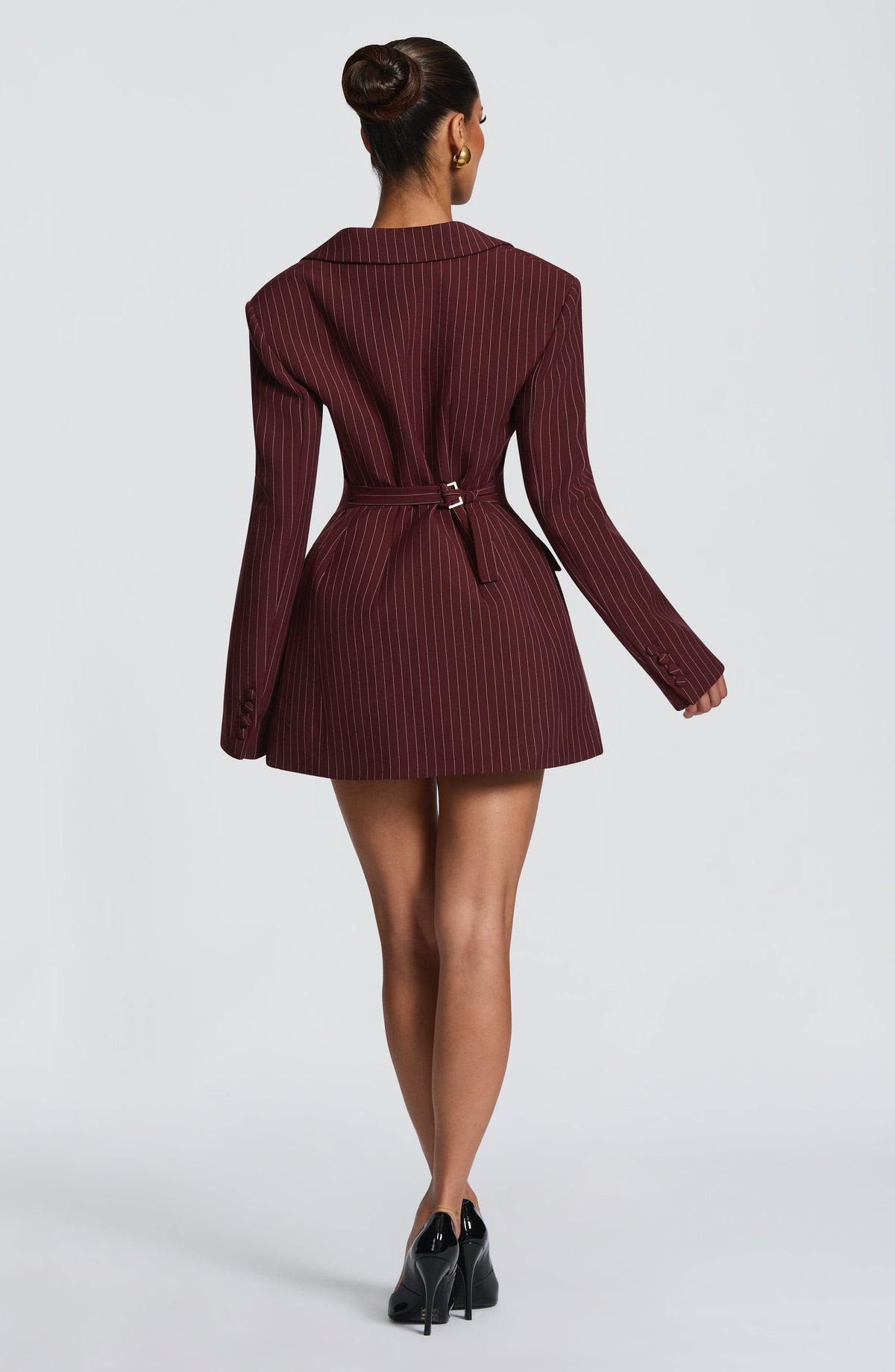 Back view of the burgundy pinstriped blazer dress with a buckled waist belt, covered cuff buttons and black patent heels. 29