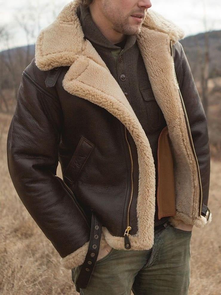 Man standing in a dry field, jacket worn open to show shearling lining, zip and buckled hem strap 8