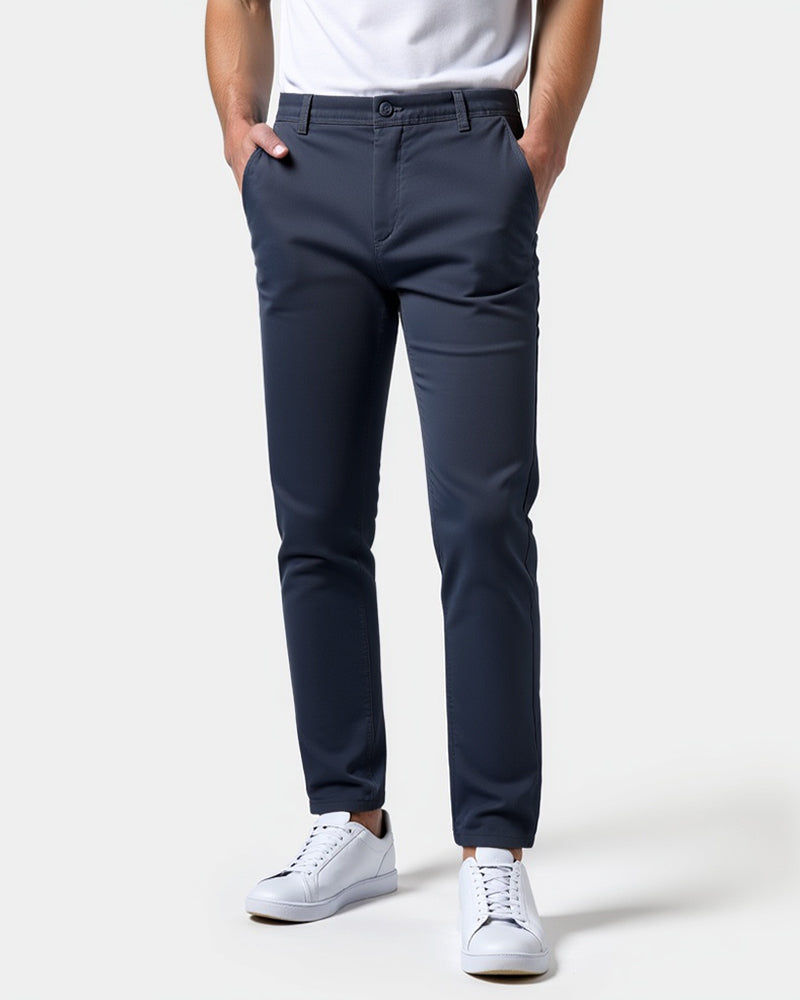 Navy blue chinos worn by a model with a white t-shirt and white trainers, front view with hands in pockets. 15