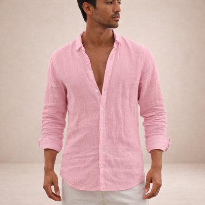 Model in a pink crinkled linen shirt with sleeves rolled up, worn open at the chest with white trousers. 1