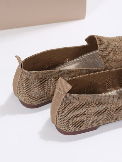 Close-up of the back of brown knit slip-ons, showing the heel pull tabs, flat sole and stitched footbed inside. 9