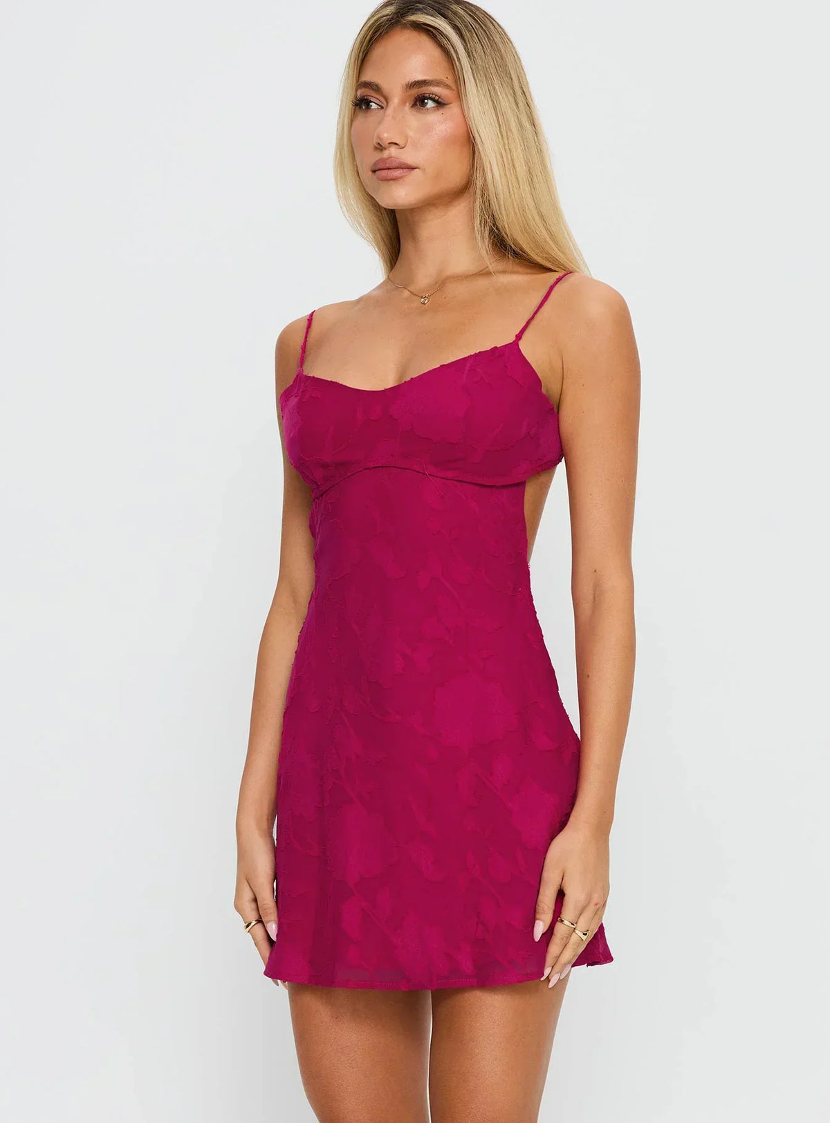 Angled side view of the mini dress, showing the low open back, thin straps and flared skirt on the model. 7