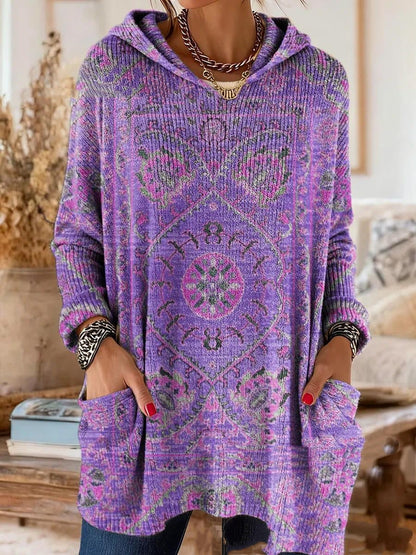 Purple version of the ribbed hooded tunic with a pink and green medallion print, worn with hands in the patch pockets. 2