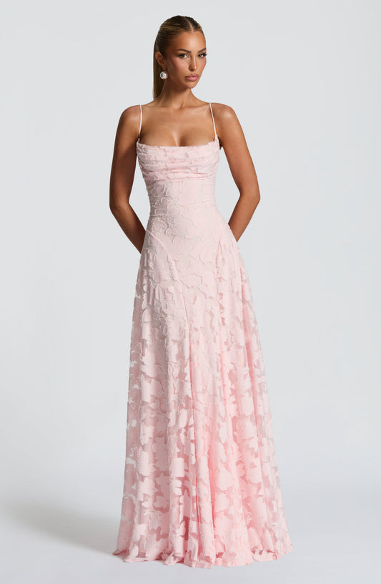 Model facing the camera in a pale pink floral jacquard maxi dress with a draped cowl neckline and thin straps. 1