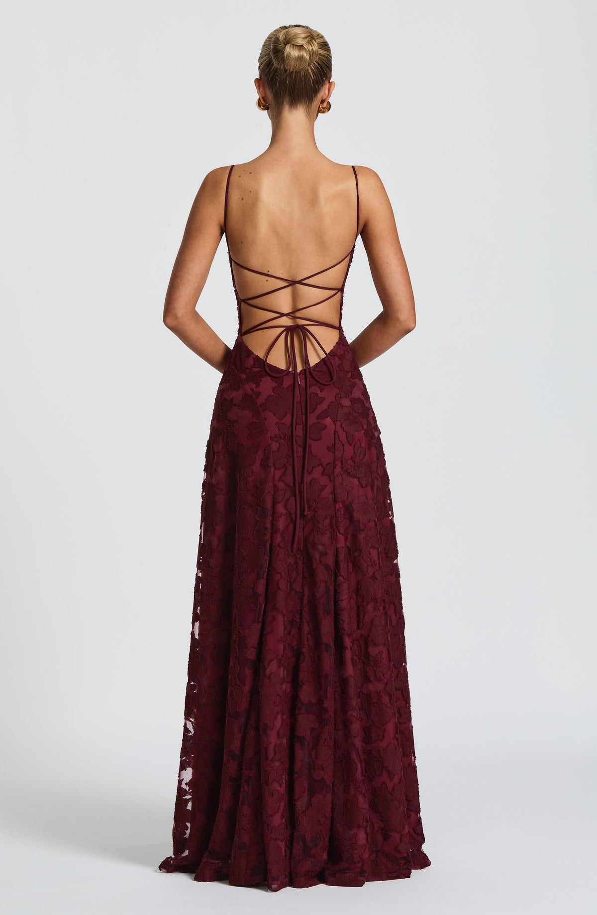 Back view of the burgundy dress showing the open back with criss-cross lace-up ties and floral textured skirt. 23