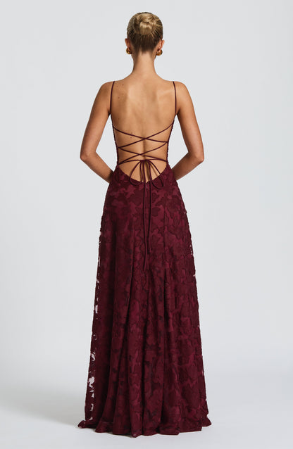 Back view of the burgundy dress showing the open back with criss-cross lace-up ties and floral textured skirt. 23