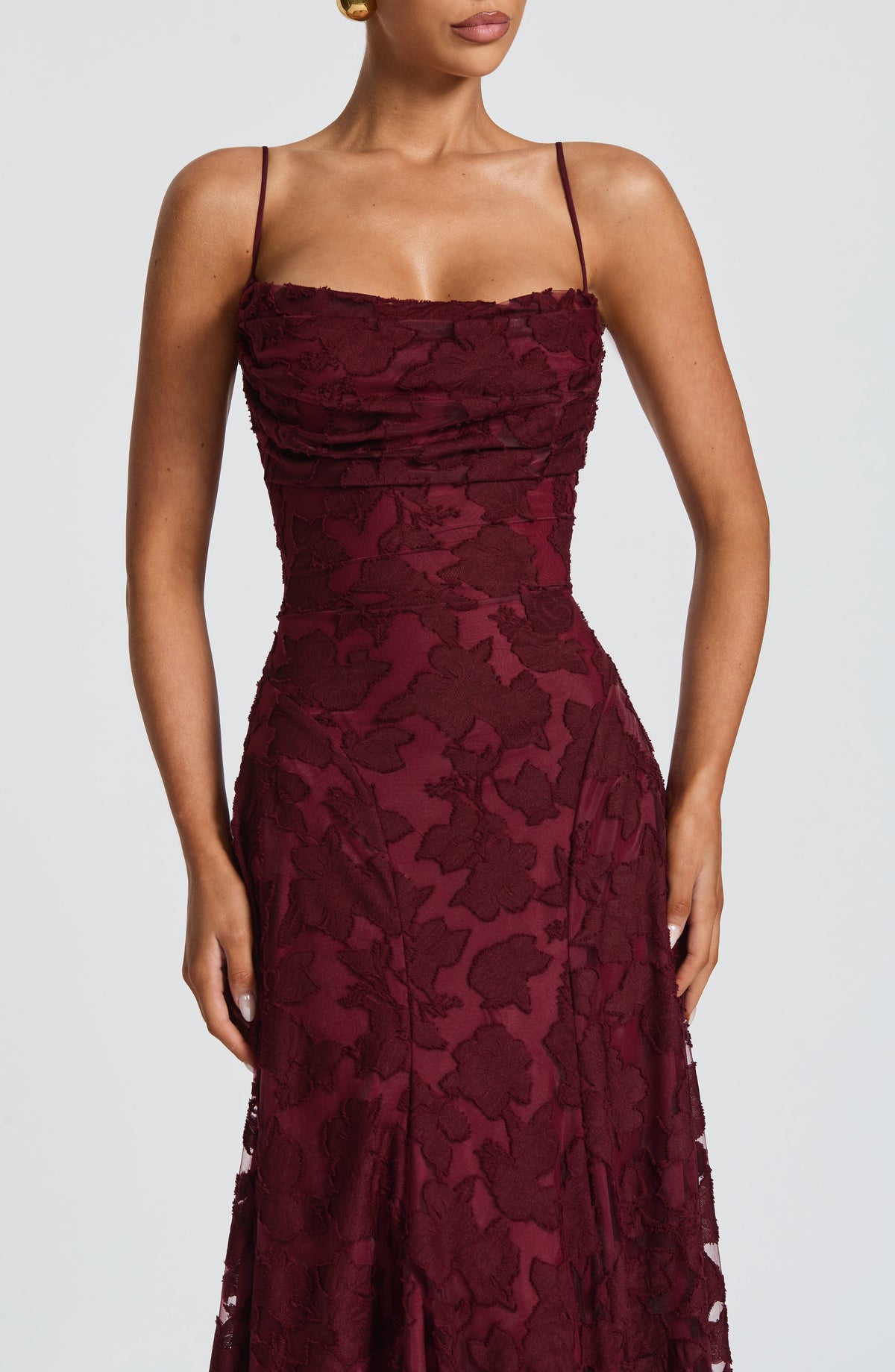 Close-up of the burgundy floral textured bodice with ruched cowl neckline and thin spaghetti straps on a model. 21