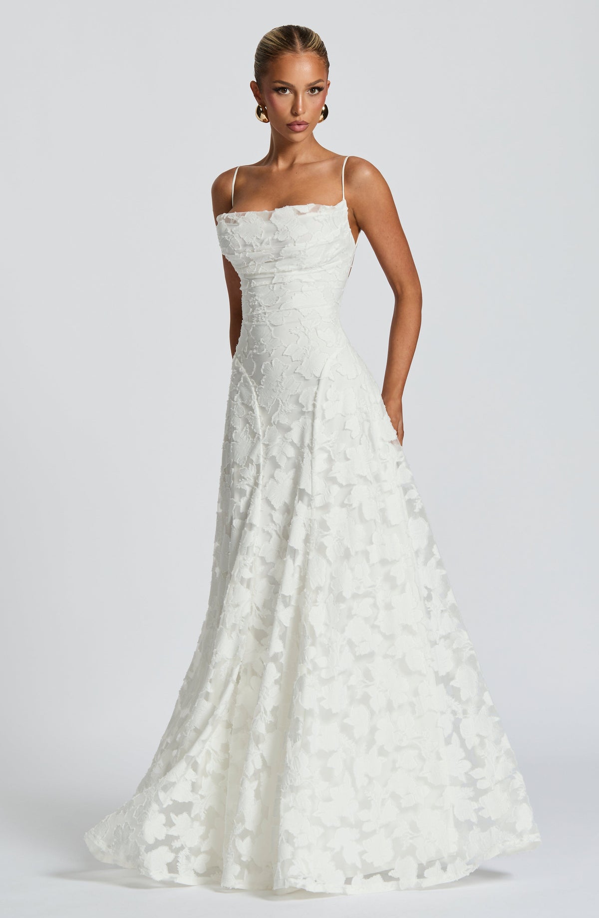 White floral maxi dress with the wide A-line skirt flaring out, worn by a model with gold earrings. 10