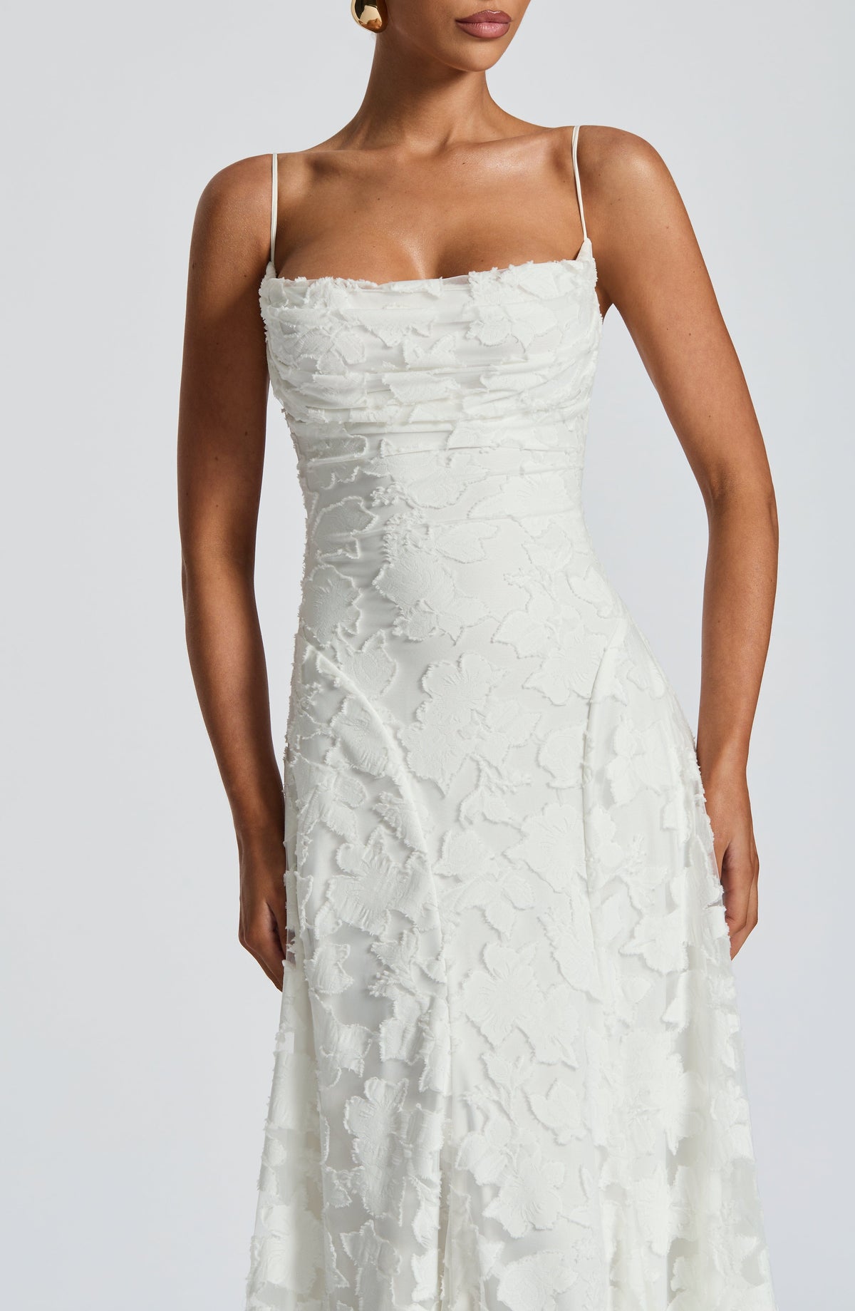 Close-up of the white dress's ruched cowl bodice, thin straps and textured floral fabric with frayed edges. 12