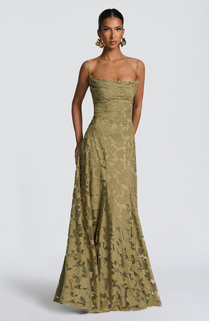 Model wearing the olive green floral textured maxi dress, front view, with large gold floral earrings. 29