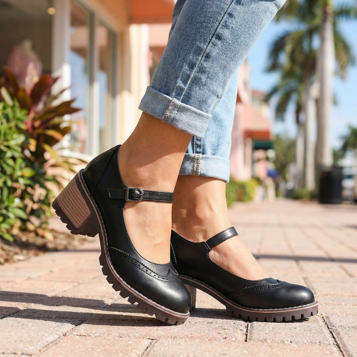 Black shoes worn outdoors on a paved street with turned-up jeans, buckle fastening and block heel visible 4