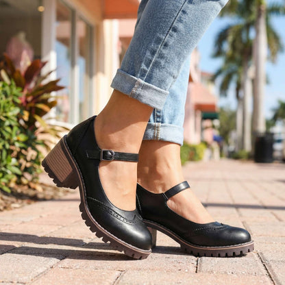 Black shoes worn outdoors on a paved street with turned-up jeans, buckle fastening and block heel visible 4