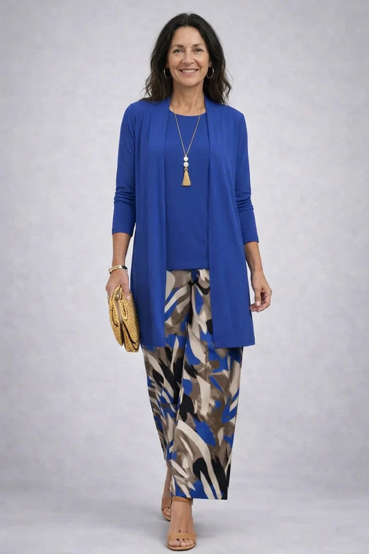 Smiling woman in a plain royal blue cardigan and top with abstract-print blue and brown trousers 2
